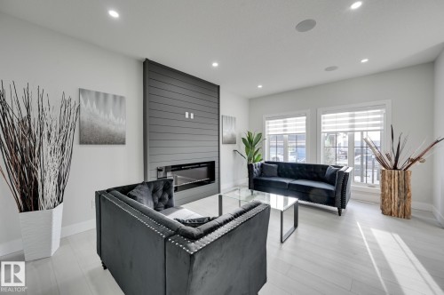 Recessed lighting, wood-finish flooring, and a linear fireplace with a shiplap feature wall - 265 Edgemont Green Nw, Edmonton, AB - Indoor Photo Showing Living Room With Fireplace