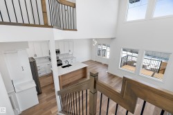 Two-story living area with high ceilings, wood-finish flooring, a contemporary kitchen, and a wooden deck - 