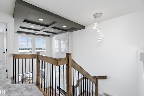 Staircase featuring wood-finish handrails, black metal balusters, and carpeted treads - 1763 Crossbill Loop Nw, Edmonton, AB - Indoor Photo Showing Other Room