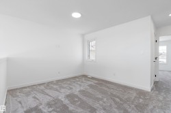 Recessed ceiling lighting, white painted walls, window with white trim, gray patterned carpeting, and white baseboards - 