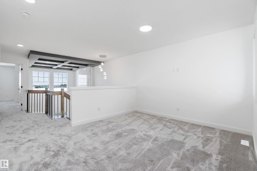 Open loft area featuring recessed lighting, a decorative ceiling treatment, a modern pendant light fixture, and a stairway with a wood newel post and metal balusters - 1763 Crossbill Loop Nw, Edmonton, AB - Indoor Photo Showing Other Room