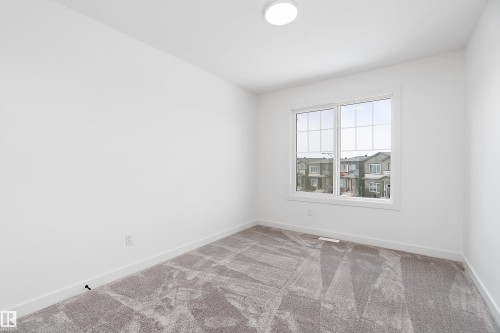 Recessed lighting, large window with multi-pane grid, plush carpeting, light-toned walls, and white trim - 1763 Crossbill Loop Nw, Edmonton, AB - Indoor Photo Showing Other Room