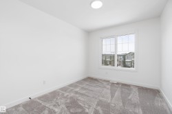 Recessed lighting, large window with multi-pane grid, plush carpeting, light-toned walls, and white trim - 