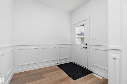 Entryway featuring wainscoting, wood-finish flooring, and a door with an inset window - 1763 Crossbill Loop Nw, Edmonton, AB - Indoor Photo Showing Other Room