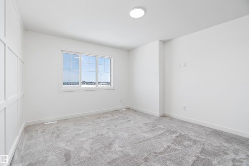 White wall paneling, light gray carpeting, recessed ceiling lighting, and a white framed window - 1763 Crossbill Loop Nw, Edmonton, AB - Indoor Photo Showing Other Room