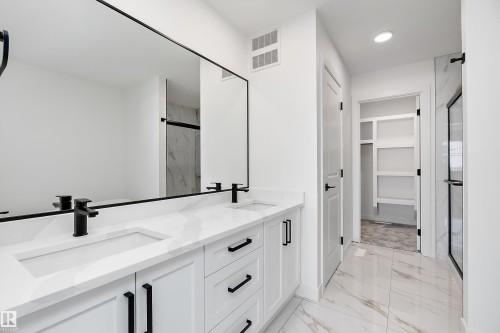 Dual vanity with integrated sinks, white cabinetry, and matte black hardware - 1763 Crossbill Loop Nw, Edmonton, AB - Indoor
