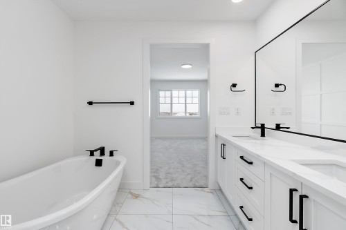 White vanity with dual sinks, black fixtures, and a freestanding bathtub - 1763 Crossbill Loop Nw, Edmonton, AB - Indoor Photo Showing Bathroom