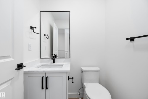 White vanity with matte black hardware, integrated rectangular sink, and stone-finish countertop - 1763 Crossbill Loop Nw, Edmonton, AB - Indoor Photo Showing Bathroom