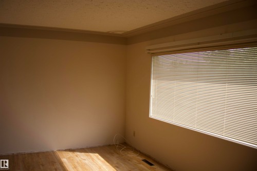 Wood-finish flooring, textured ceiling, and a window with blinds - 4946 47 Street, Barrhead, AB - Indoor Photo Showing Other Room
