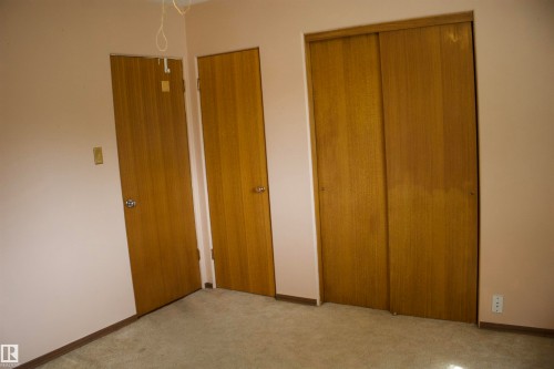 Three wood-finish doors and a sliding closet door - 4946 47 Street, Barrhead, AB - Indoor Photo Showing Other Room