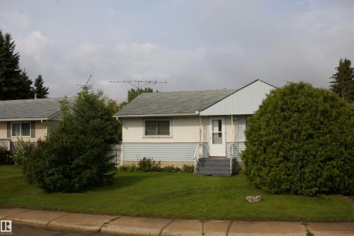 Front exterior featuring a gabled roofline, light-toned siding, and a prominent front entrance with stairs - 4946 47 Street, Barrhead, AB - Outdoor