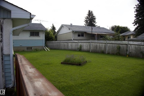 Expansive green lawn with a built-in planter, bordered by a privacy fence with lattice detailing - 4946 47 Street, Barrhead, AB - Outdoor
