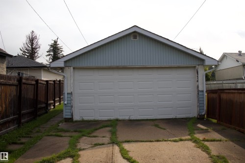 Detached garage featuring a white panel door, light blue siding, and white rain gutters - 4946 47 Street, Barrhead, AB - Outdoor With Exterior