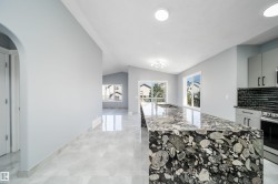 Spacious kitchen island with unique stone countertop, integrated sink, and modern cabinetry - 