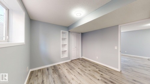 Wood-finish flooring throughout, recessed built-in shelving, white trim, and a window - 7848 7 Avenue Sw, Edmonton, AB - Indoor Photo Showing Other Room