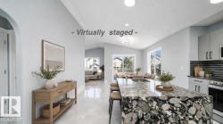 Kitchen island with a waterfall countertop featuring a unique stone pattern, recessed lighting, light gray cabinetry, stainless steel appliances, and a horizontal tile backsplash - 