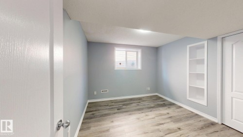 Wood-finish flooring, built-in shelving, window with blinds, and paneled doors - 7848 7 Avenue Sw, Edmonton, AB - Indoor Photo Showing Other Room