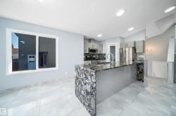 Gourmet kitchen with a waterfall island featuring a stone countertop, stainless steel appliances, and sleek cabinetry - 