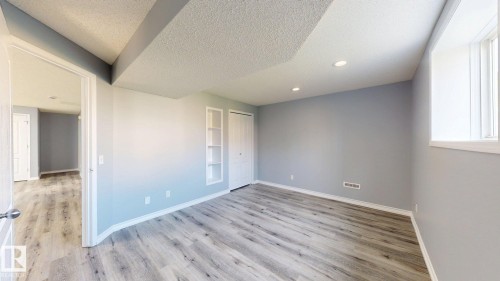 Wood-finish flooring, built-in shelving, white bi-fold closet doors, recessed lighting, and a white-trimmed window - 7848 7 Avenue Sw, Edmonton, AB - Indoor Photo Showing Other Room