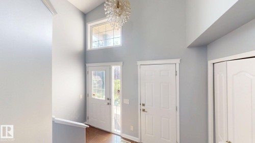 Vaulted ceiling, transom window, chandelier, wood-finish flooring, and white paneled doors - 7848 7 Avenue Sw, Edmonton, AB - Indoor Photo Showing Other Room