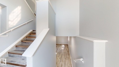 Multi-level interior featuring a staircase with wood-finish treads and white handrails - 7848 7 Avenue Sw, Edmonton, AB - Indoor Photo Showing Other Room