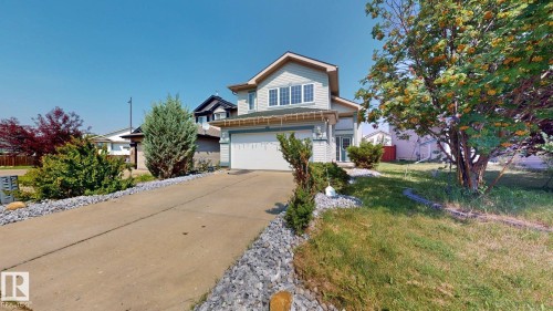 Light-colored siding exterior with a concrete driveway, attached garage, and mature trees - 7848 7 Avenue Sw, Edmonton, AB - Outdoor With Facade
