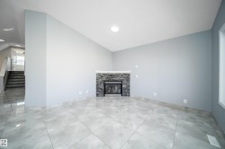 Vaulted ceiling, recessed lighting, tile flooring, stone-clad fireplace, and a large window - 