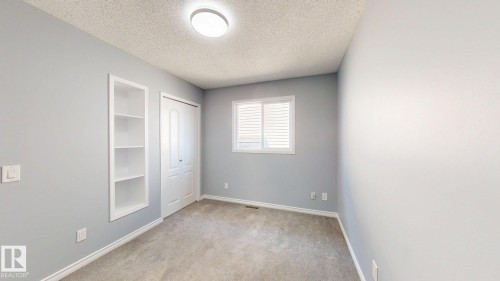 Recessed built-in shelving, white bi-fold closet doors, window with white blinds, and overhead flush-mount lighting - 7848 7 Avenue Sw, Edmonton, AB - Indoor Photo Showing Other Room