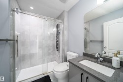 Walk-in shower with full-height tile surround, glass enclosure, and multi-function shower panel - 