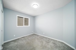 Neutral-toned carpeting, light blue wall paint, white trim, and a ceiling-mounted light fixture - 