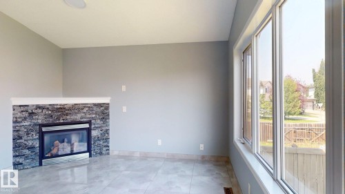 Fireplace with stone-finish surround, white mantel, and hearth - 7848 7 Avenue Sw, Edmonton, AB - Indoor With Fireplace
