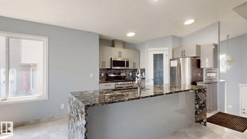 Kitchen featuring a large island with a patterned countertop, stainless steel appliances, upper and lower cabinetry, and recessed lighting - 7848 7 Avenue Sw, Edmonton, AB - Indoor Photo Showing Kitchen With Upgraded Kitchen