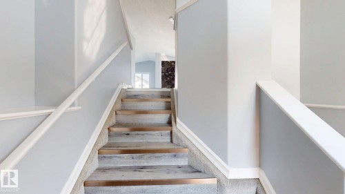 Staircase featuring wood-finish treads, carpeted risers, and white handrails - 7848 7 Avenue Sw, Edmonton, AB - Indoor Photo Showing Other Room
