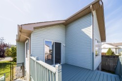 Exterior siding with a built-in deck featuring a sliding glass door and multiple windows - 