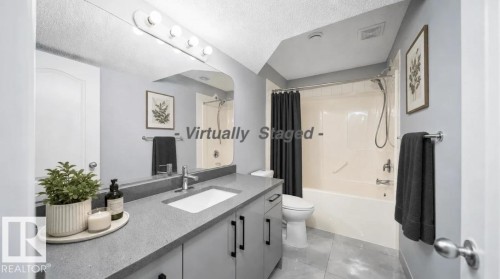 Bathroom featuring a single vanity with an integrated sink, dark countertop, and lower cabinetry - 7848 7 Avenue Sw, Edmonton, AB 