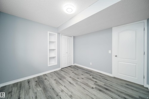 Wood-finish flooring, recessed shelving, modern ceiling light fixture, white trim, and solid panel doors - 7848 7 Avenue Sw, Edmonton, AB 