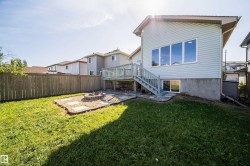 Expansive backyard featuring a wood privacy fence, a stone-bordered fire pit area, a multi-level wood deck, and a sliding glass door - 