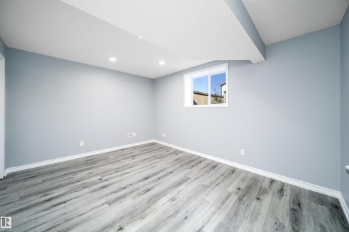 Recessed lighting, wood-finish flooring, light blue wall paint, white trim, and a window - 7848 7 Avenue Sw, Edmonton, AB 