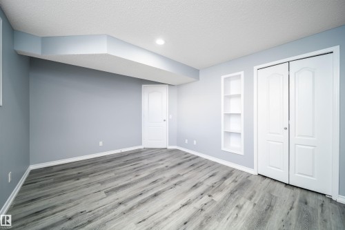 Recessed lighting illuminates the wood-finish flooring, complemented by a built-in shelving unit and two panel doors - 7848 7 Avenue Sw, Edmonton, AB 