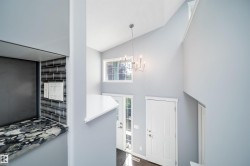 Two-story foyer with vaulted ceilings, a contemporary chandelier, transom window, and a paneled entry door with sidelights - 