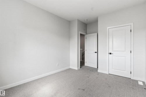 Neutral wall color, light gray carpeting, two white paneled doors, and black door hardware - 8815 181 Avenue Nw, Edmonton, AB - Indoor Photo Showing Other Room