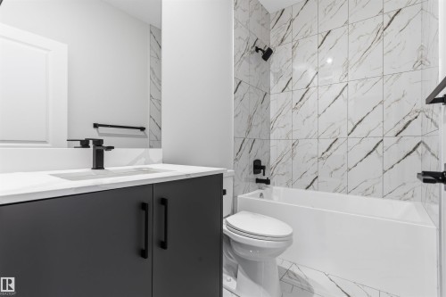 Modern bathroom featuring a dark grey vanity with matte black hardware, white countertop, and integrated rectangular sink - 8815 181 Avenue Nw, Edmonton, AB - Indoor Photo Showing Bathroom