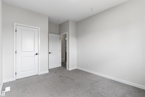 Light gray carpeting, white painted walls, white trim, and white paneled doors with matte black hardware - 8815 181 Avenue Nw, Edmonton, AB - Indoor Photo Showing Other Room
