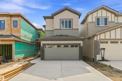 Two-story exterior with a mixed material facade, an attached garage, a concrete driveway, and a gabled roofline - 8815 181 Avenue Nw, Edmonton, AB - Outdoor