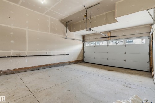 Concrete flooring, drywall walls, overhead garage door with windows, and an automatic garage door opener - 8815 181 Avenue Nw, Edmonton, AB - Indoor Photo Showing Garage