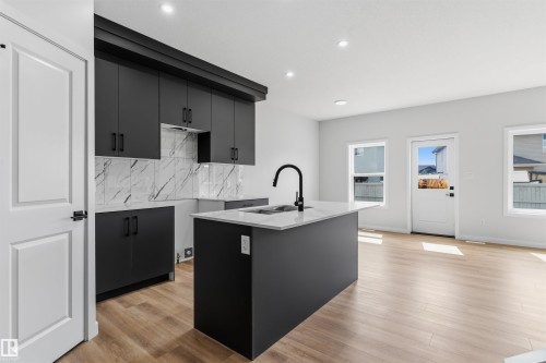 Kitchen featuring matte black cabinetry, white countertops, a white backsplash with gray veining, wood-finish flooring, and recessed lighting - 8815 181 Avenue Nw, Edmonton, AB - Indoor Photo Showing Kitchen With Upgraded Kitchen