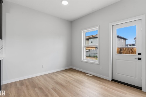 Wood-finish flooring, recessed ceiling light, white window trim, white exterior door, and black door hardware - 8815 181 Avenue Nw, Edmonton, AB - Indoor Photo Showing Other Room
