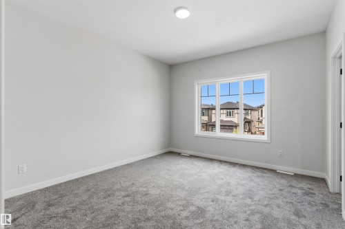 Neutral tone wall finish, plush carpeting, white trim work, white window frame, and overhead flush-mount lighting - 8815 181 Avenue Nw, Edmonton, AB - Indoor Photo Showing Other Room