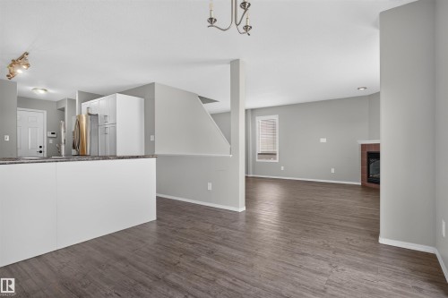 Open concept layout featuring wood-finish flooring, a built-in fireplace, and white cabinetry - 1816 36 Avenue Nw, Edmonton, AB - Indoor