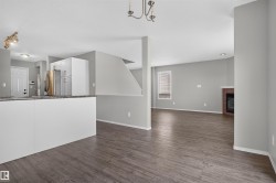 Open concept layout featuring wood-finish flooring, a built-in fireplace, and white cabinetry - 